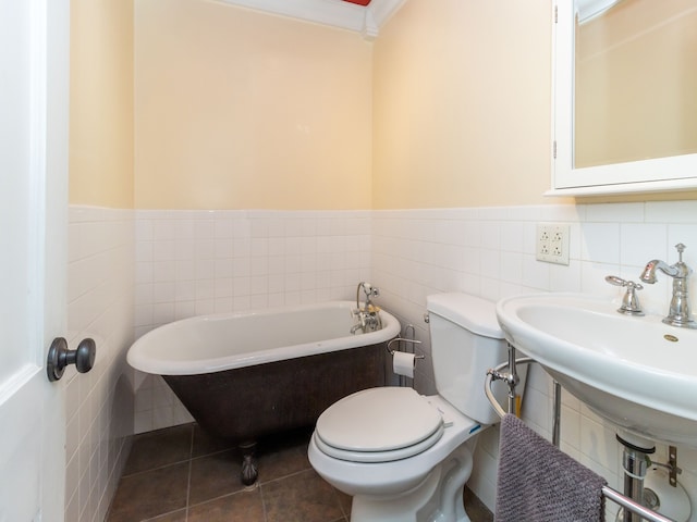 bathroom with tile patterned flooring, a bath, toilet, and tile walls