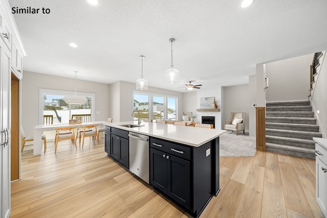 kitchen with white cabinets, sink, dishwasher, light hardwood / wood-style floors, and an island with sink