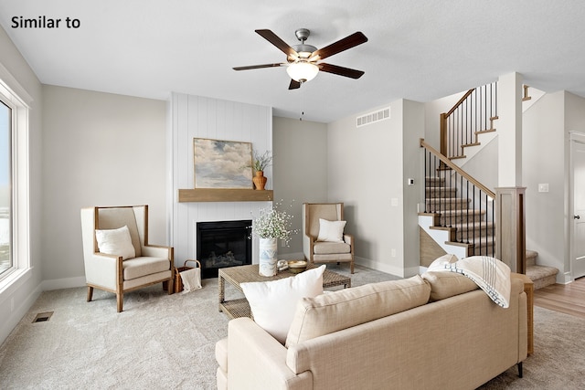 living room featuring a large fireplace, plenty of natural light, ceiling fan, and light carpet