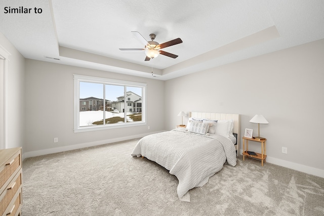 carpeted bedroom featuring a tray ceiling and ceiling fan