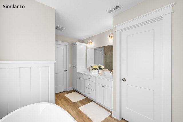 bathroom with a washtub, vanity, and hardwood / wood-style flooring