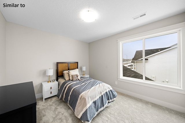 bedroom featuring light carpet and a textured ceiling