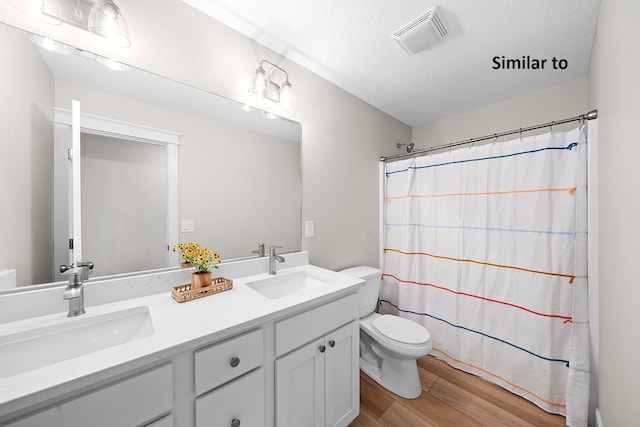 bathroom with curtained shower, hardwood / wood-style floors, a textured ceiling, toilet, and vanity