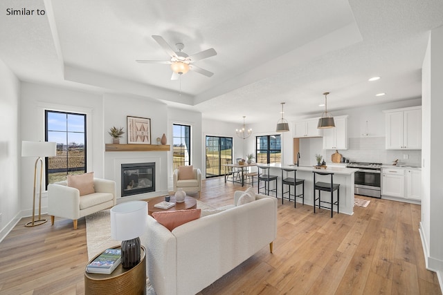 living room featuring plenty of natural light, light hardwood / wood-style floors, and a tray ceiling