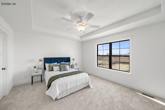 carpeted bedroom featuring ceiling fan and a tray ceiling