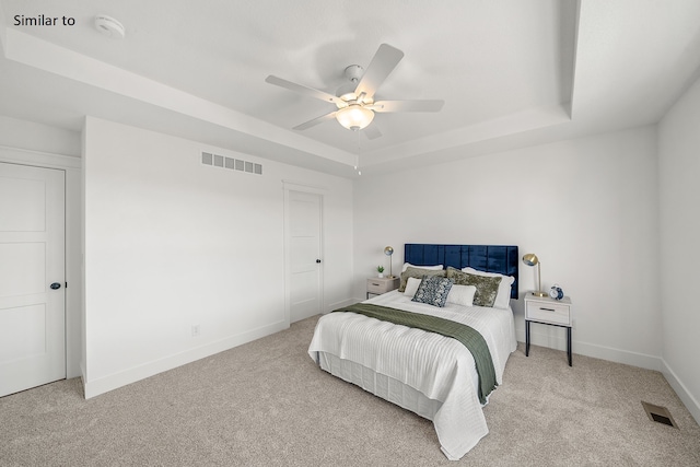 bedroom featuring light carpet, a raised ceiling, and ceiling fan