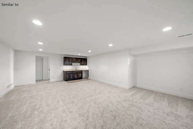 basement with indoor bar and light colored carpet