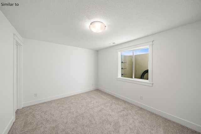 carpeted spare room with a textured ceiling