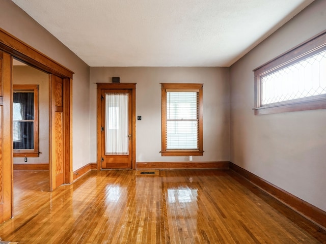 empty room with a textured ceiling and light wood-type flooring