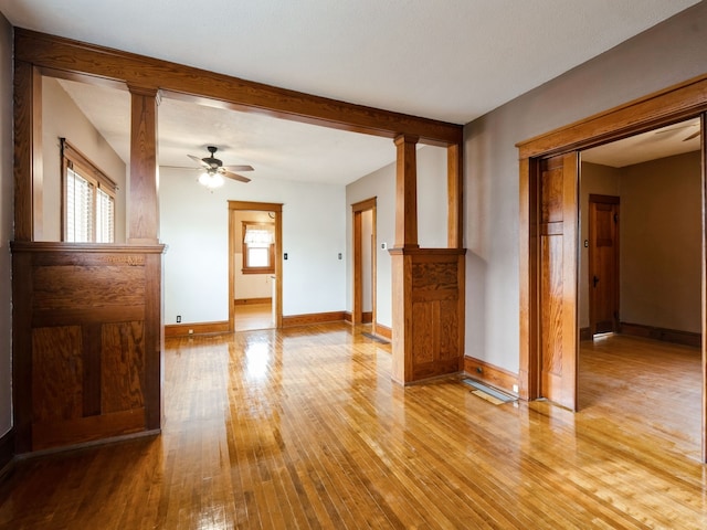 interior space featuring ornate columns, ceiling fan, and light wood-type flooring