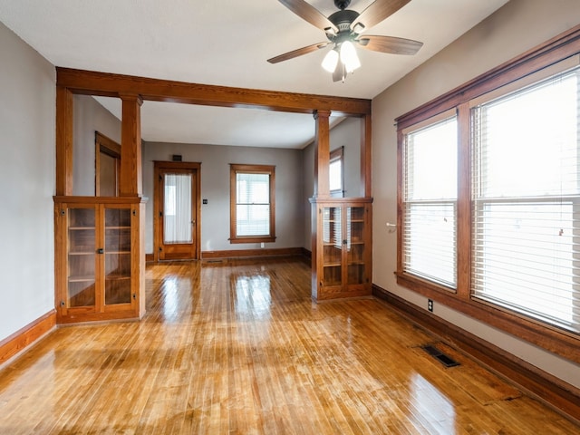 unfurnished living room featuring decorative columns, light hardwood / wood-style flooring, and plenty of natural light