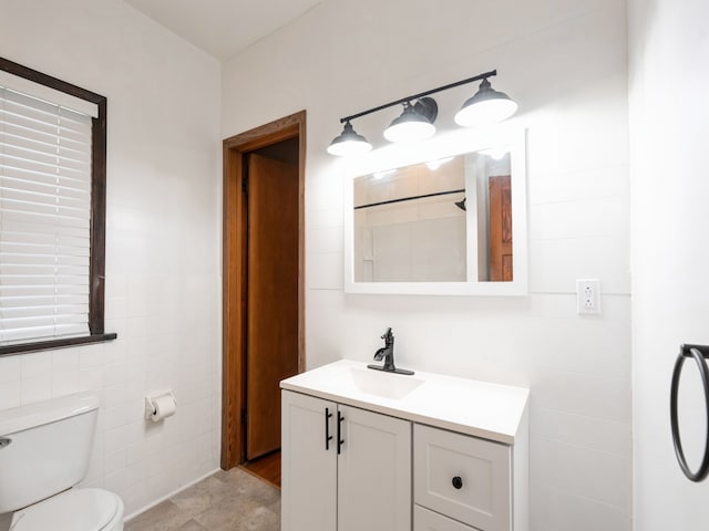 bathroom featuring vanity, toilet, and tile walls