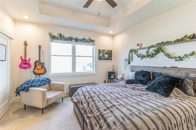 carpeted bedroom featuring ceiling fan and a tray ceiling