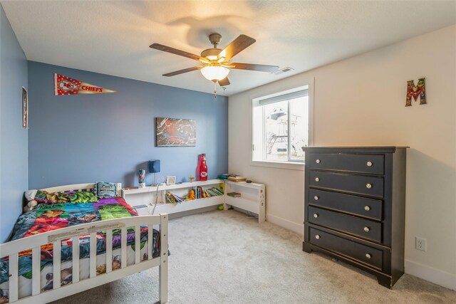 carpeted bedroom with ceiling fan and a textured ceiling