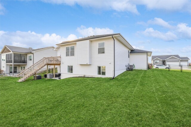 rear view of property with a lawn, a wooden deck, and central AC