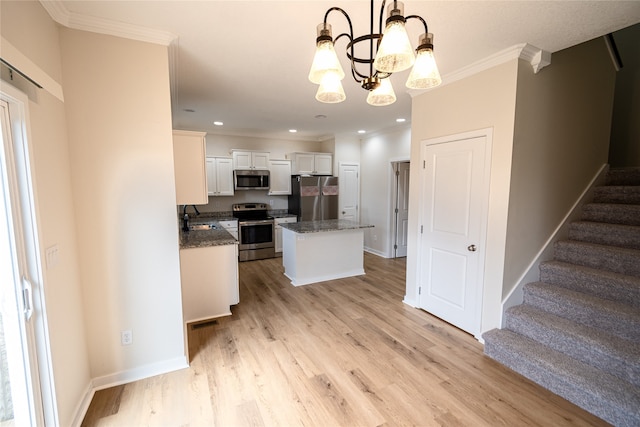 kitchen featuring hanging light fixtures, an inviting chandelier, a kitchen island, white cabinets, and appliances with stainless steel finishes