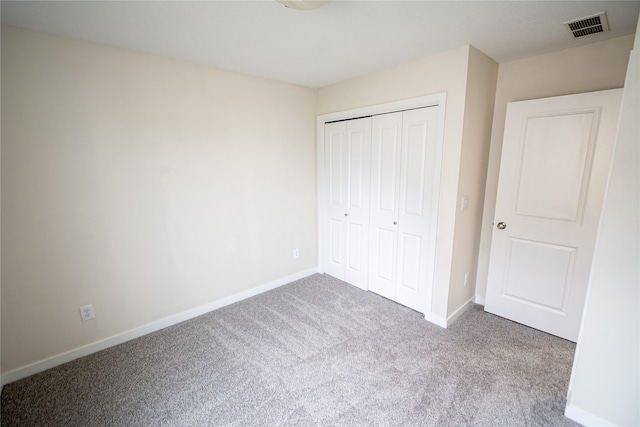 unfurnished bedroom with light colored carpet and a closet