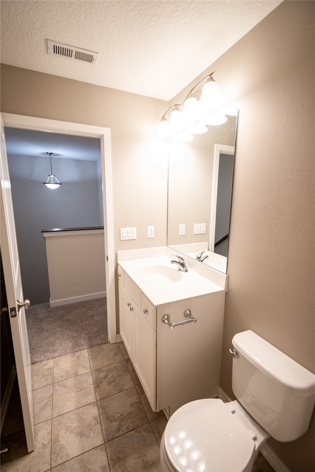 bathroom with tile patterned flooring, vanity, a textured ceiling, and toilet