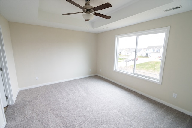 carpeted spare room featuring a raised ceiling and ceiling fan