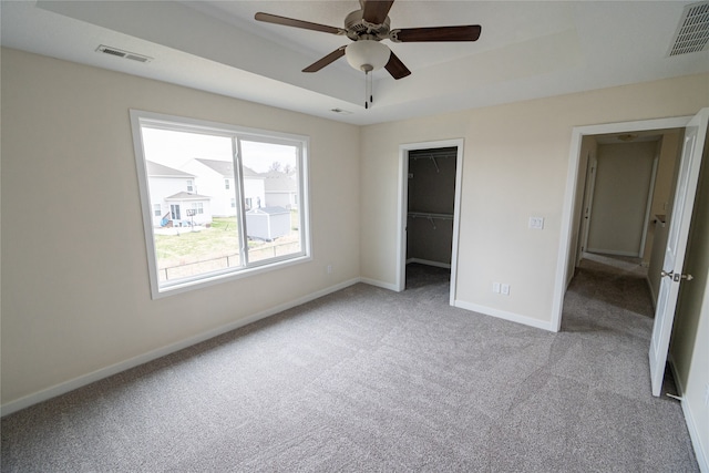 unfurnished bedroom featuring ceiling fan, light colored carpet, a spacious closet, and a closet