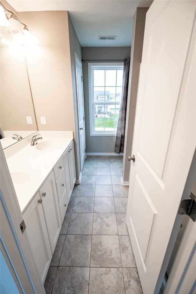 bathroom with tile patterned flooring, a textured ceiling, and vanity