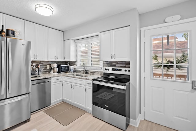 kitchen featuring white cabinets, stainless steel appliances, light hardwood / wood-style flooring, and sink