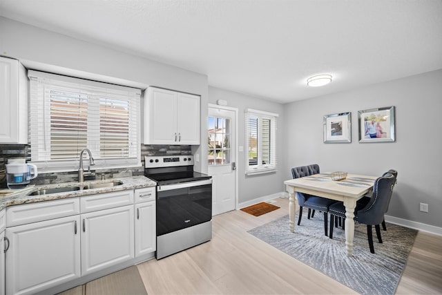 kitchen with tasteful backsplash, sink, white cabinets, light hardwood / wood-style floors, and stainless steel electric range