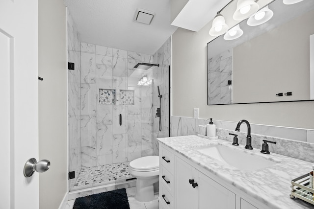 bathroom featuring a textured ceiling, vanity, toilet, and a shower with shower door