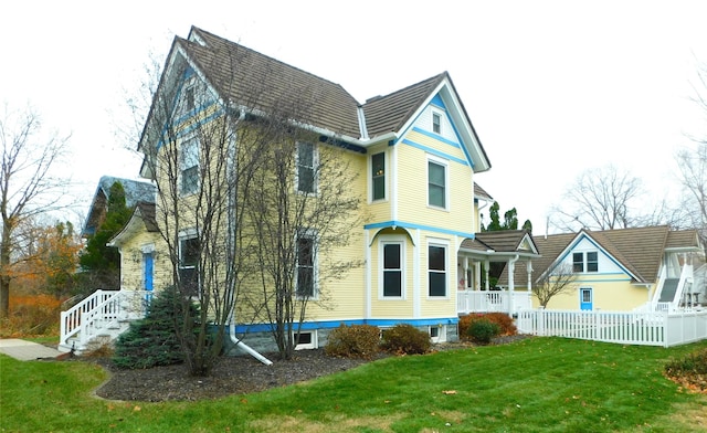 rear view of property featuring a yard and covered porch