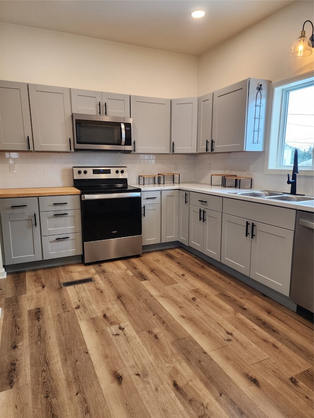 kitchen with appliances with stainless steel finishes, gray cabinets, and sink