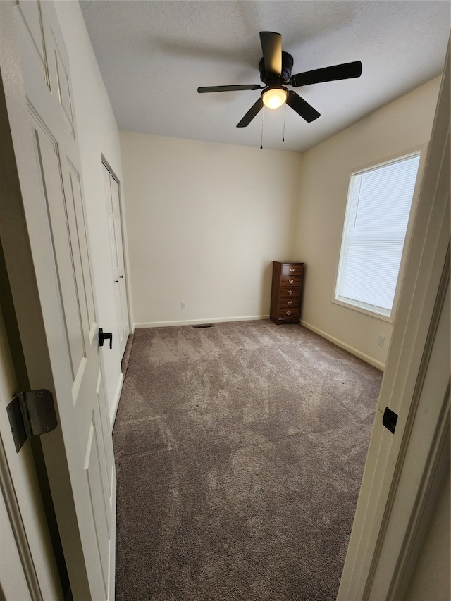 unfurnished bedroom featuring ceiling fan and dark colored carpet