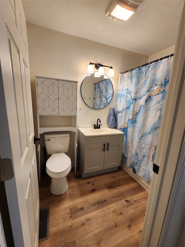 bathroom featuring hardwood / wood-style floors, vanity, toilet, a textured ceiling, and walk in shower