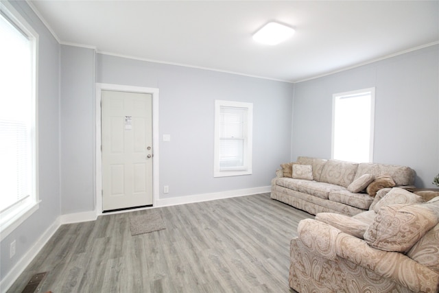 living room featuring crown molding, a healthy amount of sunlight, and light hardwood / wood-style floors