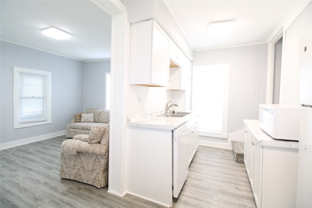 kitchen featuring white appliances, crown molding, sink, light hardwood / wood-style flooring, and white cabinets