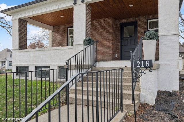 entrance to property featuring covered porch and brick siding