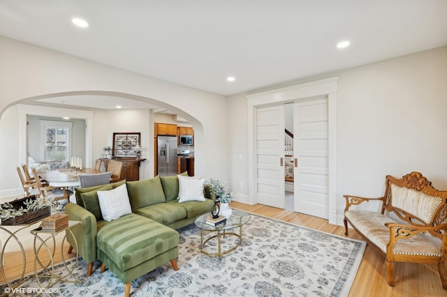 living area with arched walkways, light wood finished floors, and recessed lighting