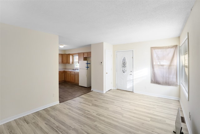 unfurnished living room with sink, light hardwood / wood-style floors, and a textured ceiling