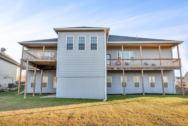 back of property featuring central AC unit, a balcony, and a yard