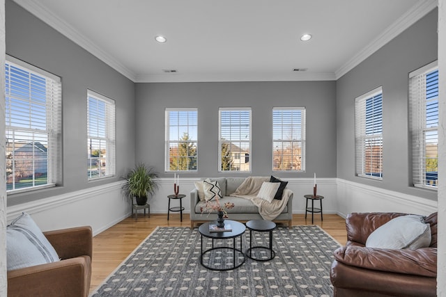 living room with a healthy amount of sunlight, crown molding, and light hardwood / wood-style flooring