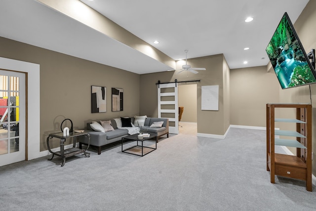 carpeted living room with a barn door and ceiling fan