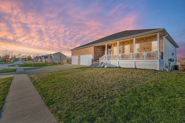 ranch-style home featuring a lawn, a porch, and a garage