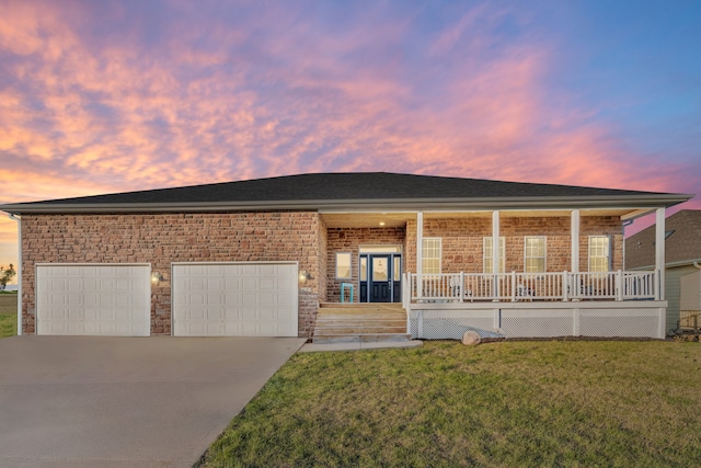 view of front of property featuring a lawn, a porch, and a garage