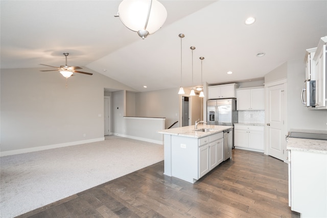 kitchen featuring pendant lighting, lofted ceiling, a center island with sink, appliances with stainless steel finishes, and white cabinetry