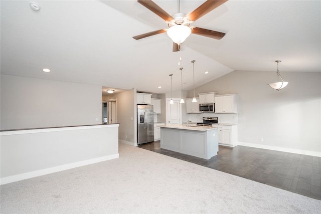 kitchen featuring white cabinetry, pendant lighting, vaulted ceiling, a kitchen island with sink, and appliances with stainless steel finishes