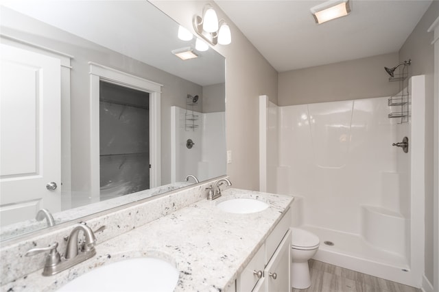 bathroom featuring hardwood / wood-style flooring, toilet, vanity, and walk in shower