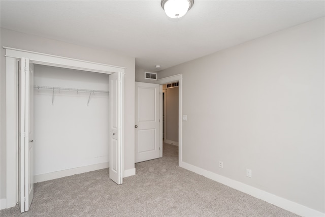 unfurnished bedroom with a closet and light colored carpet