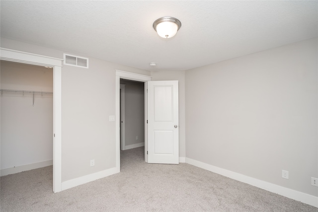 unfurnished bedroom with a spacious closet, a closet, and light colored carpet