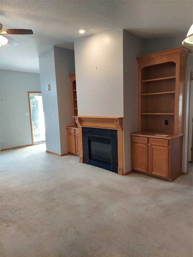 unfurnished living room with ceiling fan, a fireplace, light colored carpet, and a textured ceiling