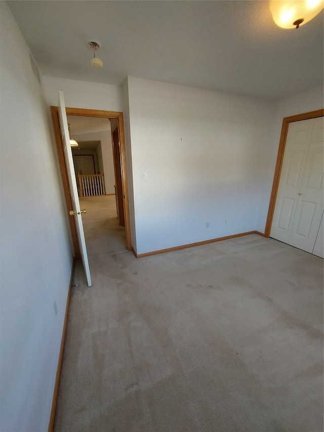 unfurnished bedroom with light carpet and a closet