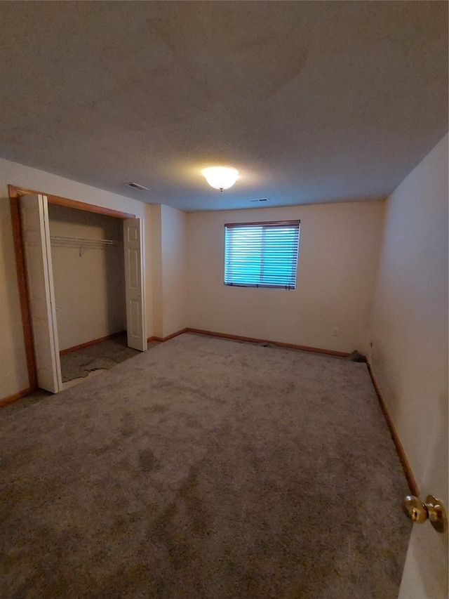 unfurnished bedroom featuring carpet flooring, a textured ceiling, and a closet